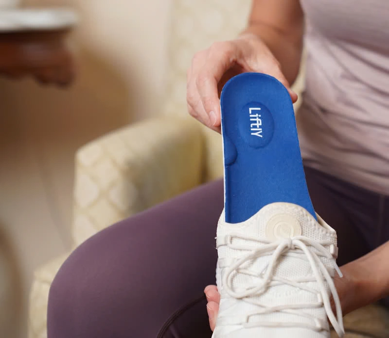 Placing a Liftly insole into a white sneaker