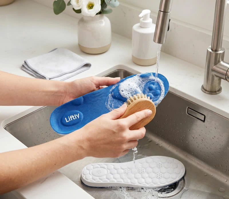 Washing Liftly insoles by hand with a brush in a sink